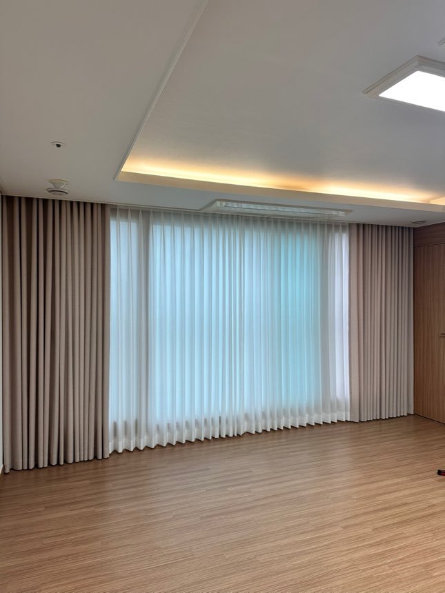 Wave stiliaus užuolaidų kompozicija per visą sieną: smėlio šoninės užuolaidos ir dieninis tiulis centre